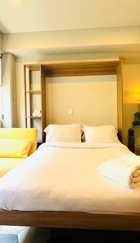 Casa Ocho studio bedroom with white bed, yellow armchair, and warm lighting